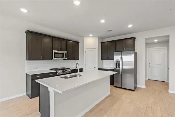 a kitchen with stainless steel appliances a microwave sink refrigerator and cabinets