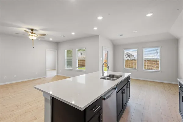 a kitchen with stainless steel appliances granite countertop a stove a sink a refrigerator and a dining table with wooden floor