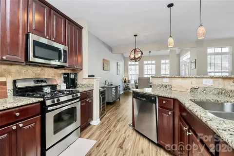 a kitchen with stainless steel appliances granite countertop a stove a sink and a microwave