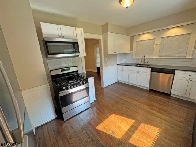 a kitchen with granite countertop white cabinets and stainless steel appliances