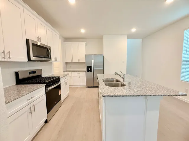 a kitchen with stainless steel appliances granite countertop a sink a stove top oven a counter space and cabinets