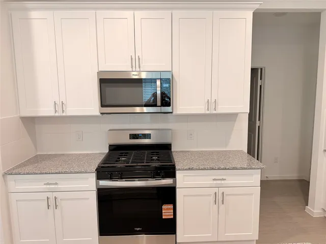a kitchen with granite countertop white cabinets and black appliances