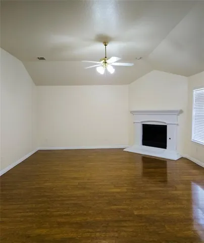 a view of an empty room with kitchen and a window