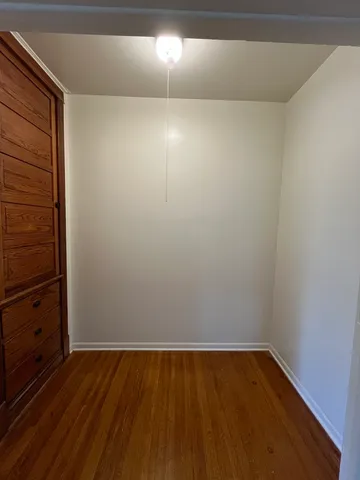 a view of an empty room with wooden floor and cabinet