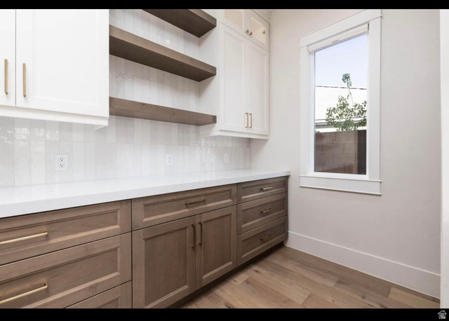 2788 East Rill Drive Washington, UT 84780 - Photo 10 of 41 Contemporary cabinetry featuring white upper cabinets and wood-finish lower cabinets, complemented by a white countertop and vertical subway tile backsplash
