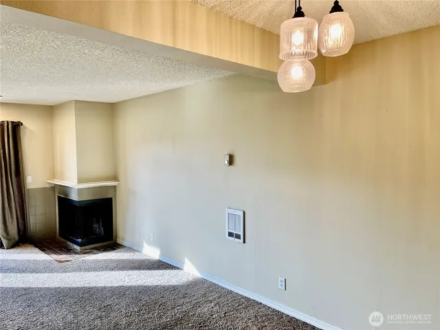 a view of an empty room with wooden floor and a chandelier