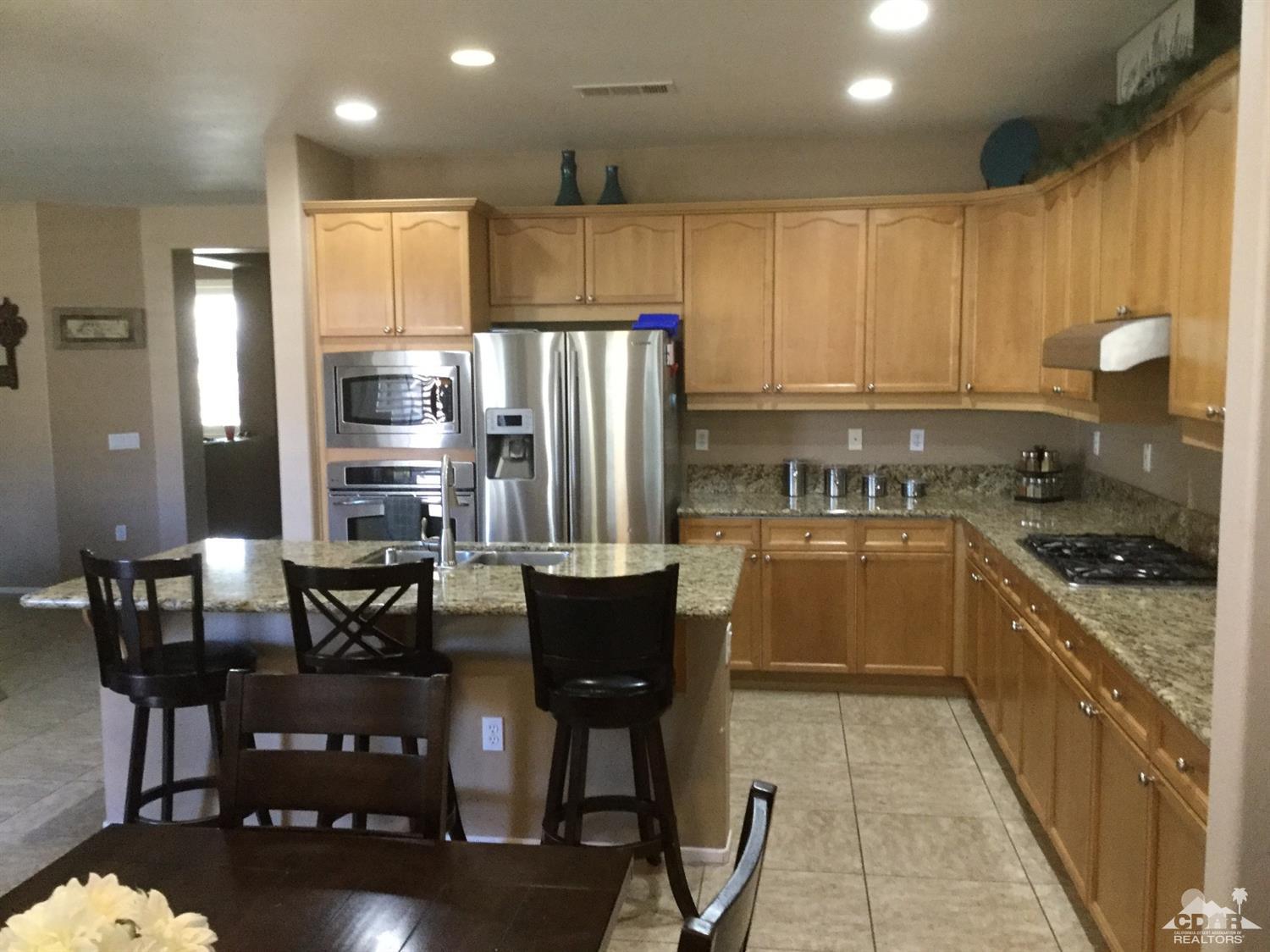 83316 Lone Star Road Indio, CA 92203 - Photo 4 of 43 a kitchen with stainless steel appliances granite countertop a stove top oven a refrigerator a dining table and chairs