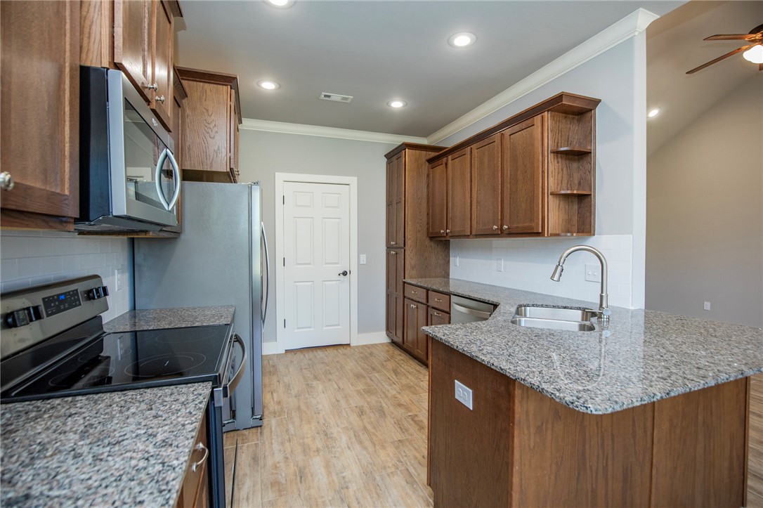 214 Alder Street Pea Ridge, AR 72751 - Photo 9 of 20 Kitchen featuring wood-finish cabinetry, granite countertops, stainless steel appliances, and wood-finish flooring