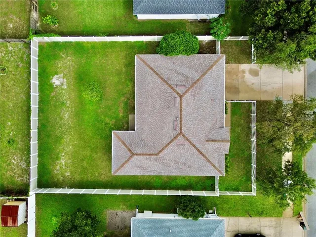 a view of a white house with a big yard and potted plants and large trees