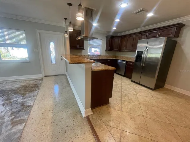 a kitchen with stainless steel appliances kitchen island granite countertop a refrigerator and a sink
