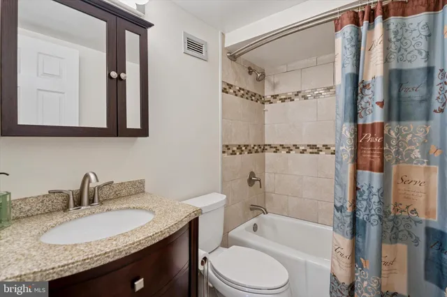 a bathroom with a granite countertop sink toilet a mirror a bathtub and shower