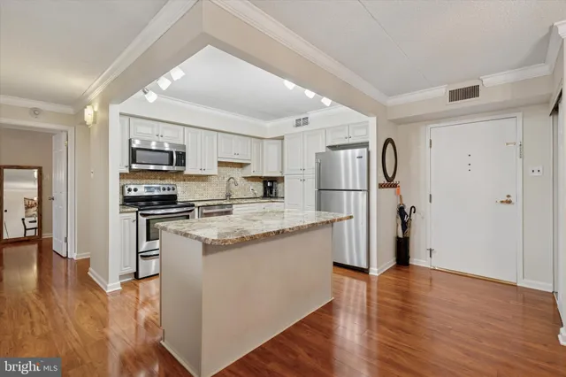 a kitchen with stainless steel appliances granite countertop a refrigerator stove and wooden floor