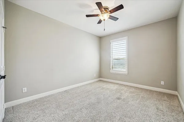 an empty room with closet and a ceiling fan