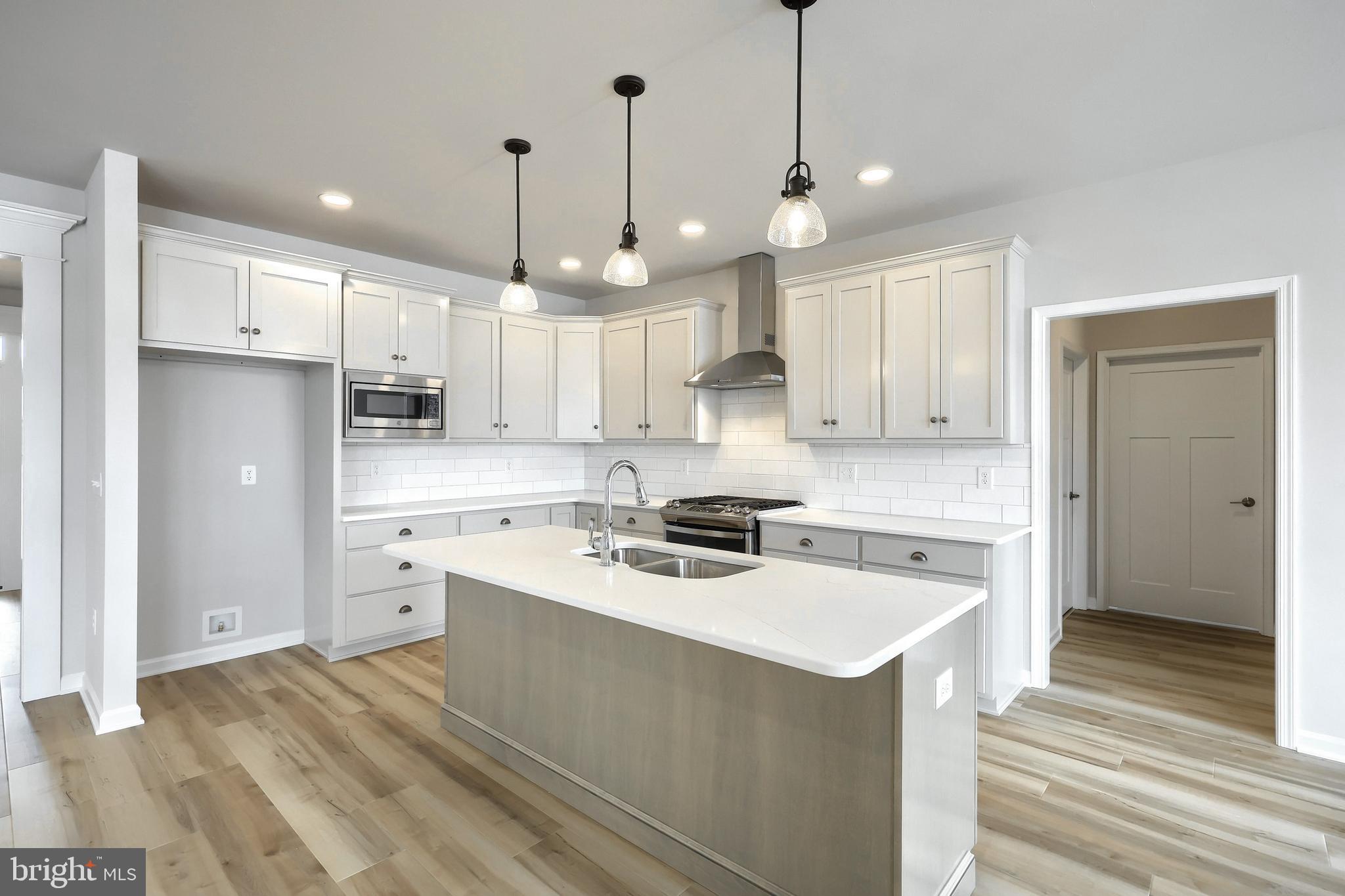 567 Lumber Street Littlestown, PA 17340 - Photo 35 of 62 a kitchen with a stove a sink a refrigerator and white cabinets with wooden floor