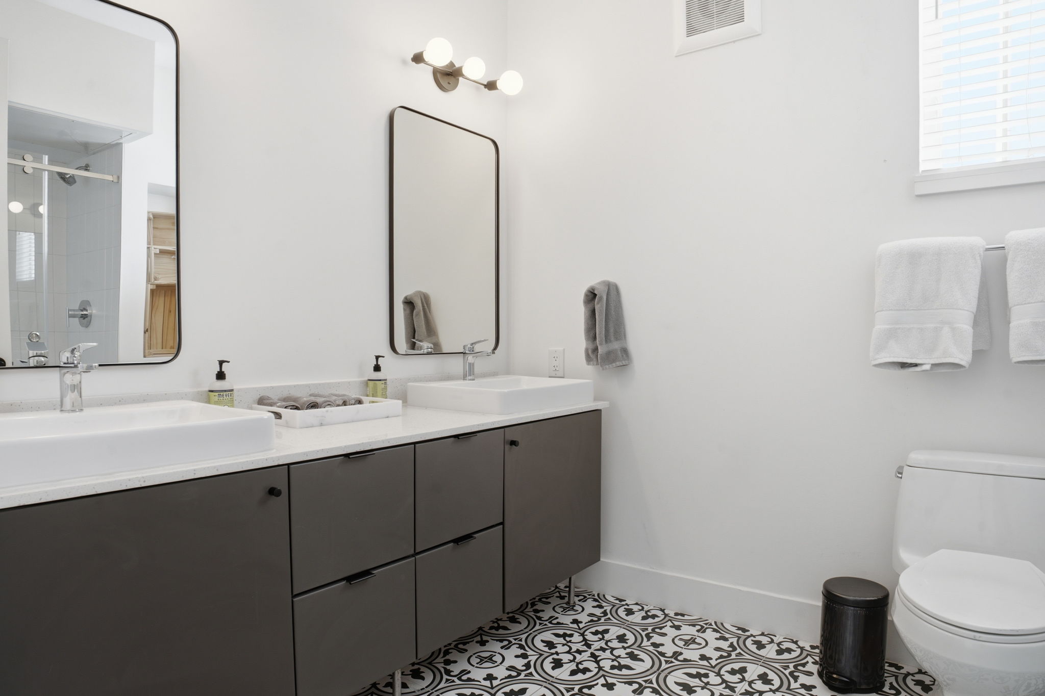2709 East 5th Street, Unit 1306 Austin, TX 78702 - Photo 12 of 28 Bold patterned tile flooring anchors this contemporary bathroom with dual vanities and modern fixtures.