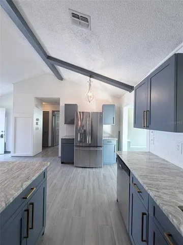 a kitchen with granite countertop a counter top space a sink stainless steel appliances and cabinets