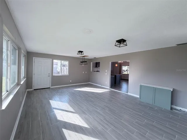 a view of an empty room with window and wooden floor