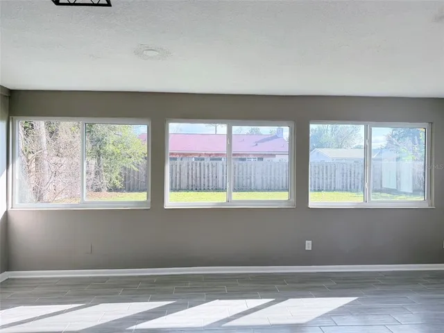 a view of an empty room with a window and wooden floor