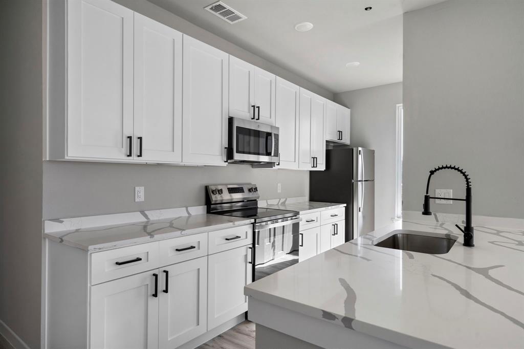 948 Corinth Street, Unit 5 Dallas, TX 75215 - Photo 10 of 28 Kitchen with stainless steel appliances, white cabinetry, light stone countertops, and light wood-type flooring