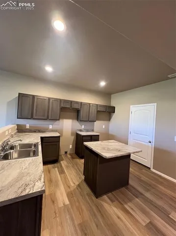a kitchen with kitchen island a counter top space a sink and cabinets
