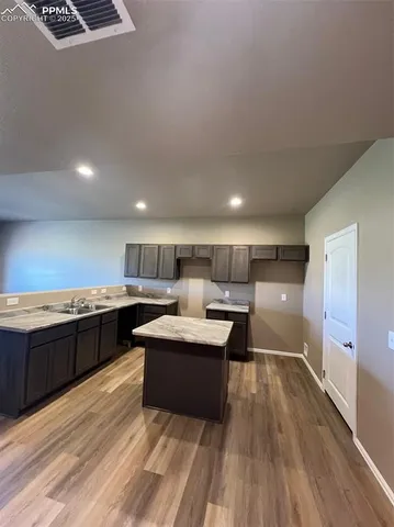 a large kitchen with a large counter top a sink stainless steel appliances and cabinets