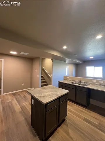 a large kitchen with a stove a sink dishwasher and a refrigerator with wooden floor