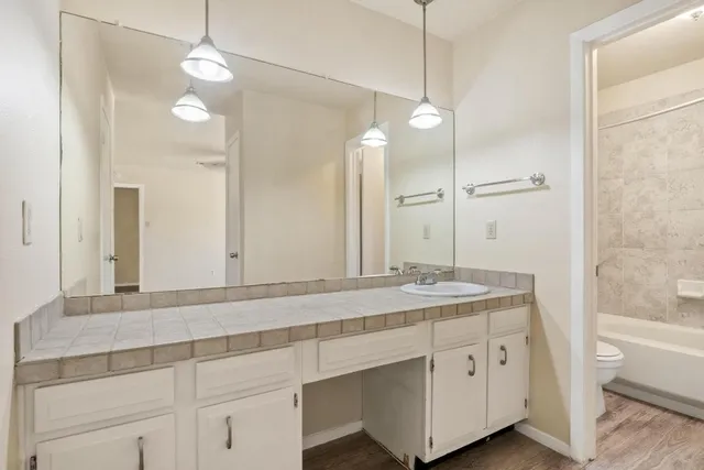 a bathroom with a granite countertop sink a toilet a mirror and shower