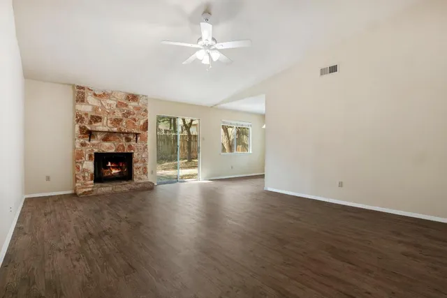 a view of an empty room with wooden floor and a fireplace