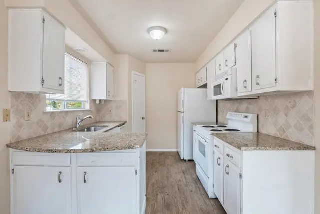 a kitchen with granite countertop a sink stove refrigerator and cabinets