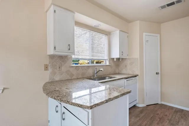 a kitchen with granite countertop a sink stove and cabinets