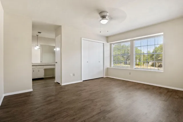 an empty room with wooden floor and windows
