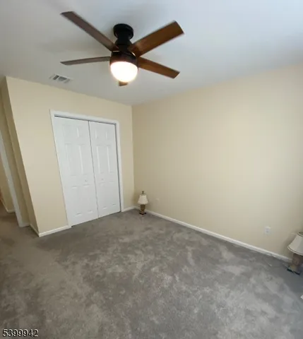 an empty room with a ceiling fan and carpet