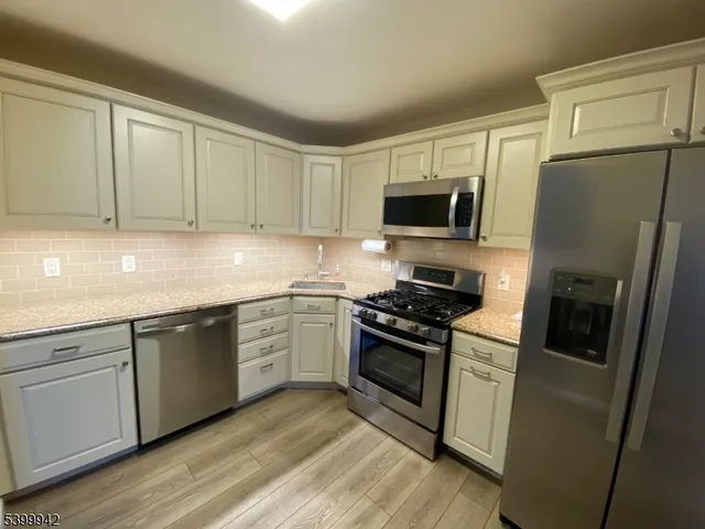a kitchen with stainless steel appliances granite countertop a stove top oven a sink and a refrigerator