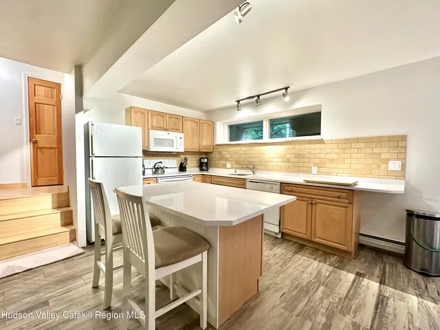 a kitchen with stainless steel appliances a stove top oven a sink dishwasher and a refrigerator with wooden floor