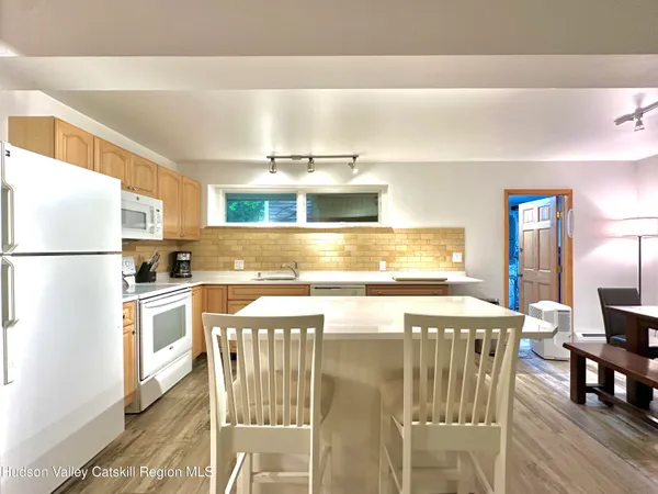 a living room with stainless steel appliances kitchen island granite countertop furniture and a flat screen tv