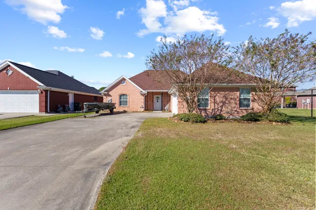 a front view of a house with a big yard and large trees