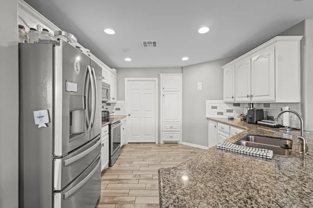 a kitchen with stainless steel appliances granite countertop a refrigerator and a stove top oven