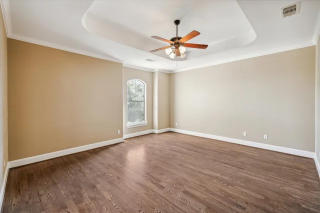 an empty room with wooden floor fan and windows