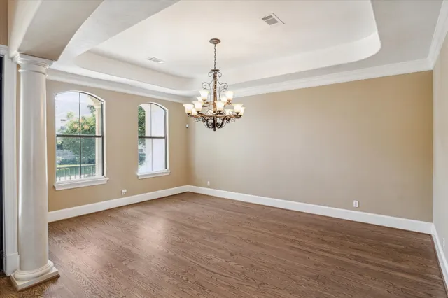 a view of a room with wooden floor chandelier and windows