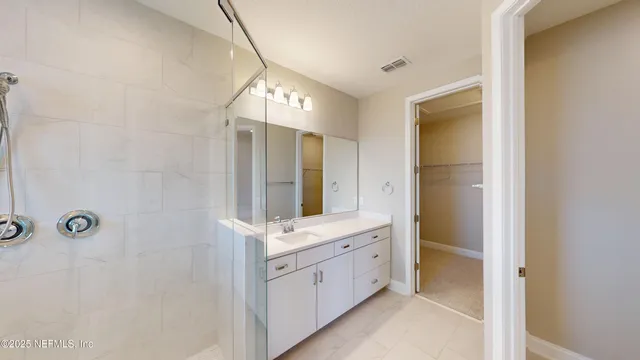 a spacious bathroom with a double vanity sink a mirror and shower