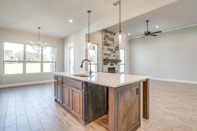 a kitchen with stainless steel appliances a sink a window a chandelier and wooden floor