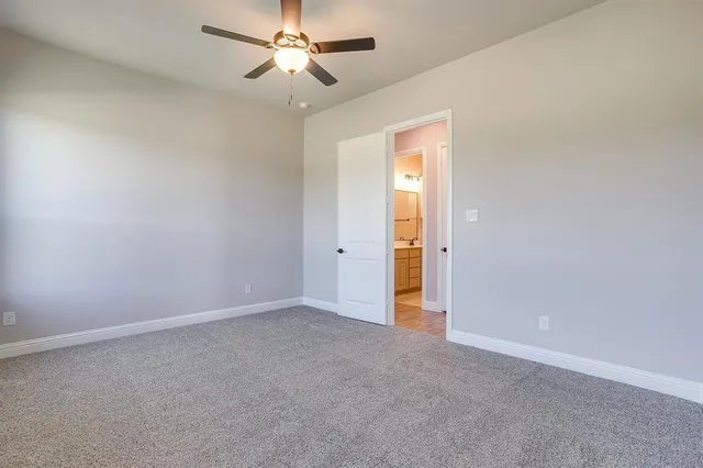 an empty room with a ceiling fan and carpet