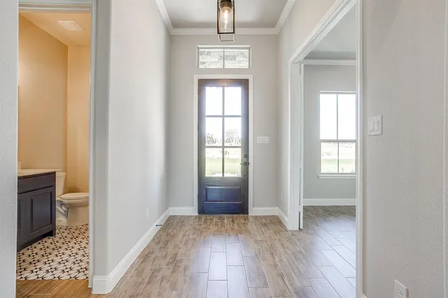 an empty room with wooden floor cabinet and windows