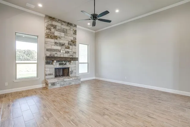an empty room with wooden floor a ceiling fan and windows