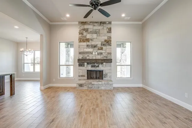 an empty room with wooden floor fireplace and windows