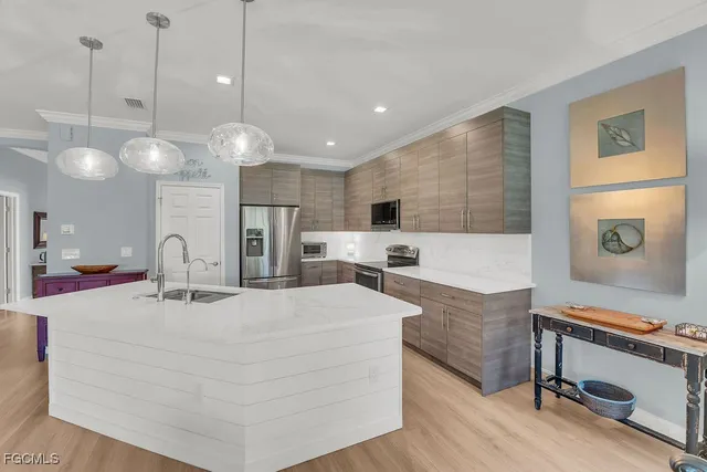 a large white kitchen with a large island oven a stove and a refrigerator with wooden floor