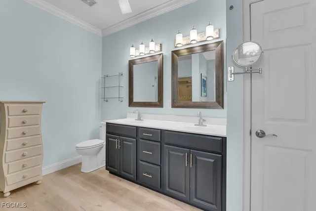 a bathroom with a toilet a double vanity sink and a mirror