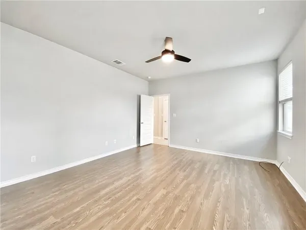 a view of an empty room with wooden floor and a window