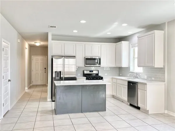 a kitchen with stainless steel appliances granite countertop a refrigerator and a stove top oven