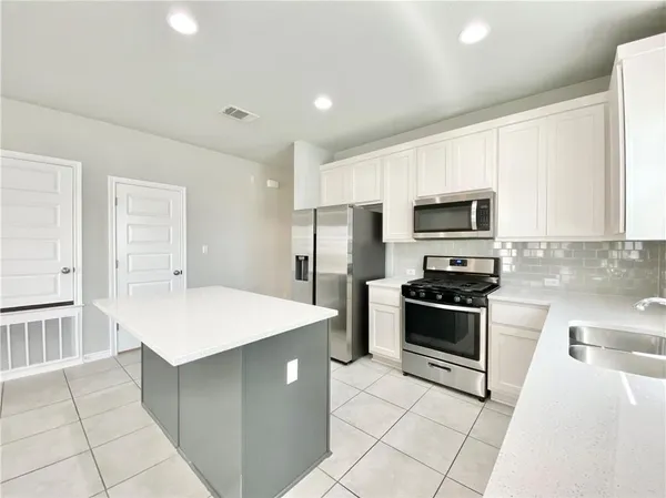 a kitchen with stainless steel appliances a stove refrigerator sink and microwave